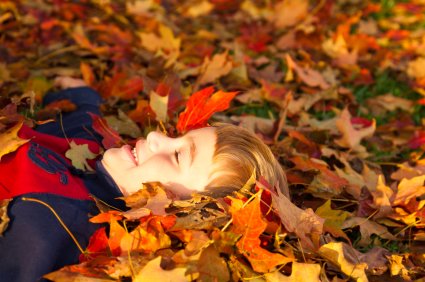 Ilustrační obrázek - šťastné dítě ležící na zádech v listí