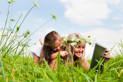 Ilustrační obrázek - maminka s dcerou leží v trávě a dívají se do notebooku