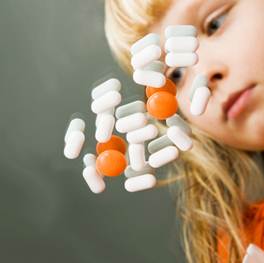 ilustrační obrázek - dívka s hromádkou léků