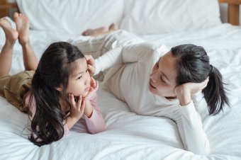 Maminka a dcera si povídají na posteli [fotograf Ketut Subiyanto]