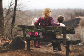 Žena s dětmi na lavičce v přírodě