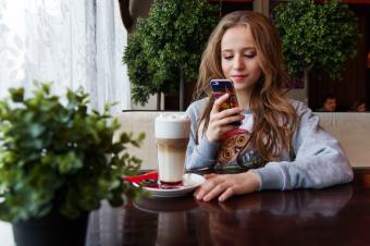 Dospívající dívka v kavárně píše na mobilu
