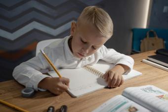 Chlapec píše úkol do sešitu