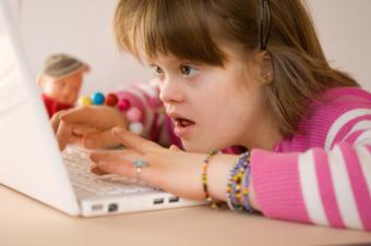 Mentálně postižená dívka a laptop Mentálně postižená dívka a laptop
