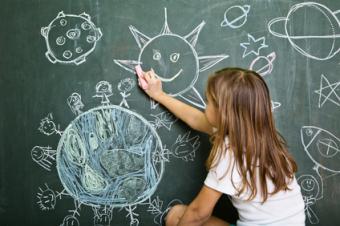 Dívka si kreslí křídou na tabuli