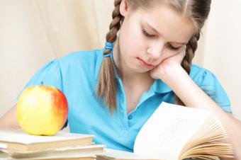 Studující dívka, knihy a jablko