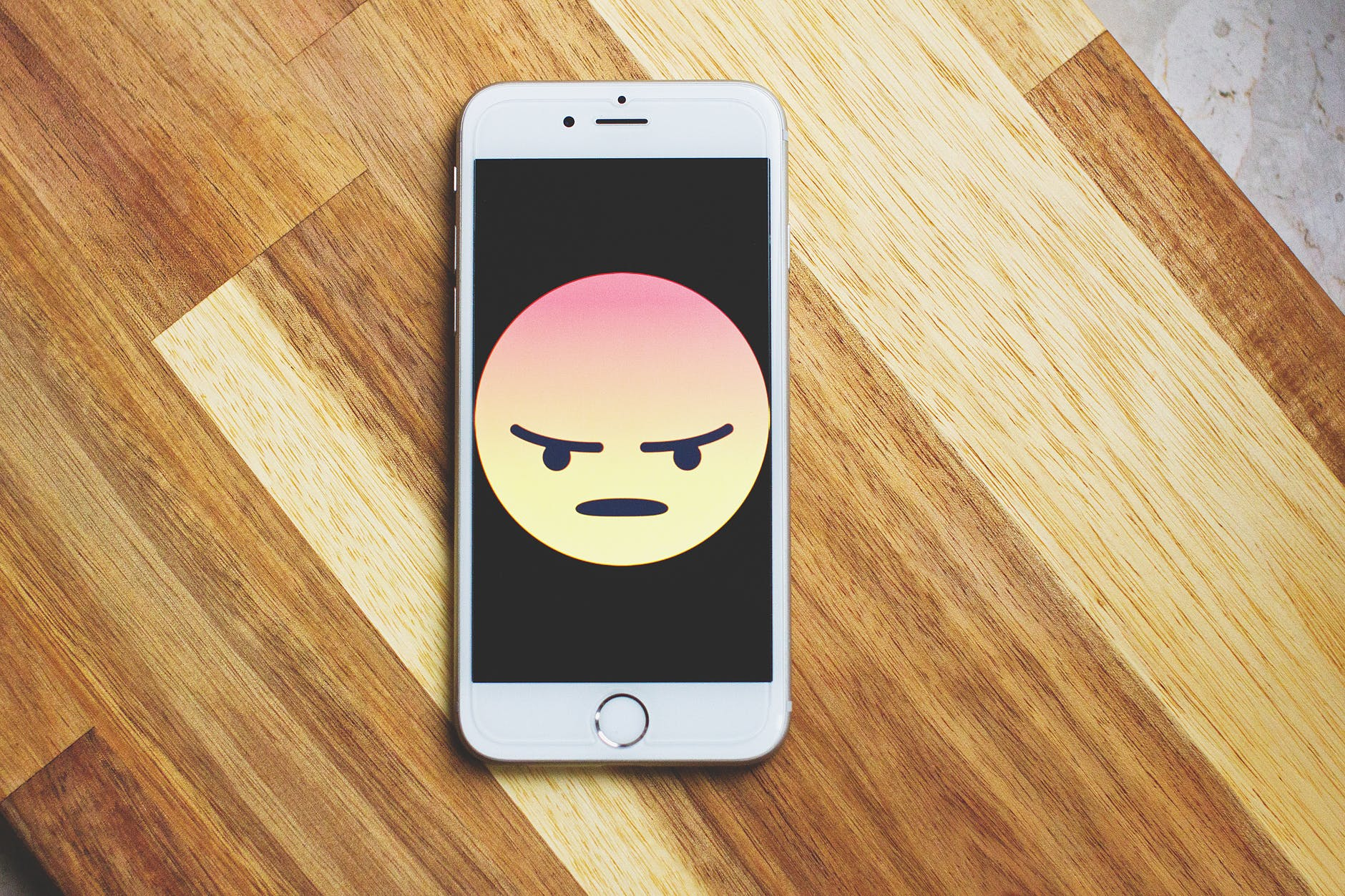 Rozzlobený smajlík na displeji mobilního telefonu Rozzlobený smajlík na displeji mobilního telefonu