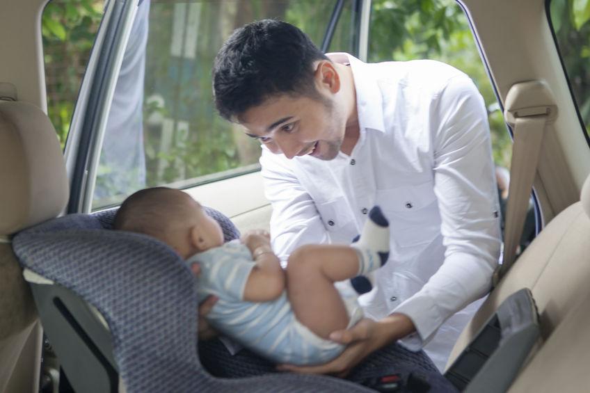 Otec dává dítě do autosedačky Otec dává dítě do autosedačky