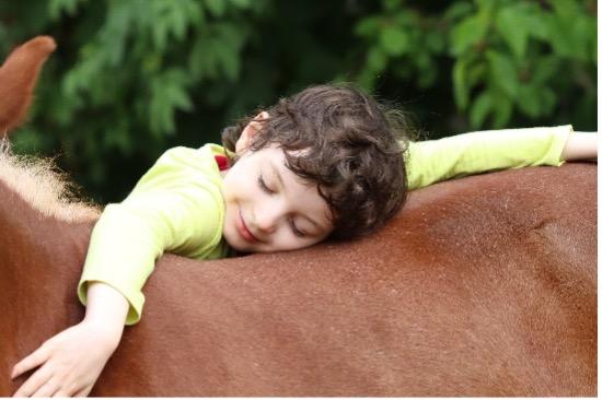 Dítě leží na hřbetu koně