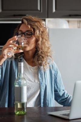 Mladá žena pije bílé víno