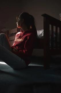 Smutná dívka opřená o postel