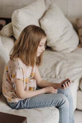 Mladá dívka sedí smutně na posteli