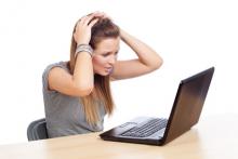 Zoufalá žena sedí před počítačem a drží se za hlavu