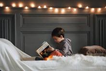 Chlapec si čte v posteli knihu