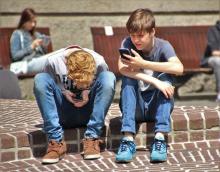 Dva mladí kluci si hrají na mobilu