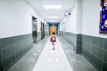 Dívka běží po školní chodbě