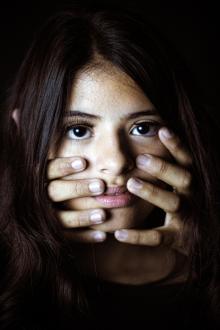 Obličej dívky zakrytý rukama násilníka