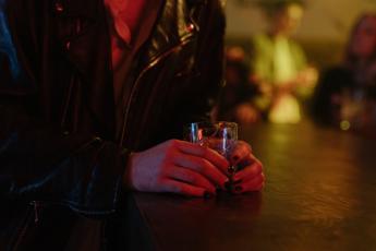Žena v ruce drží sklenici s alkoholem Žena v ruce drží sklenici s alkoholem