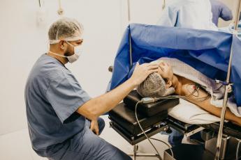 Muž sedí u ženy během operace
