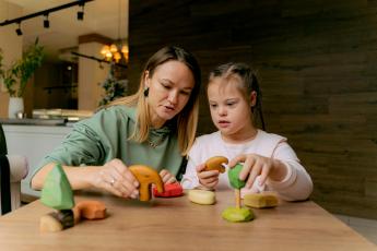 Dívka s Downovým syndromem si hraje s hračkami Dívka s Downovým syndromem si hraje s hračkami