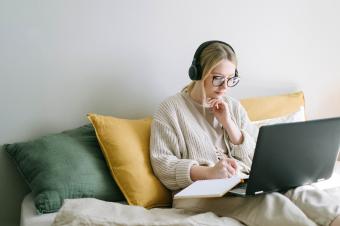 Žena na pohovce s laptopem a sluchátky