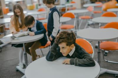 Smutný chlapec sedí sám u stolu